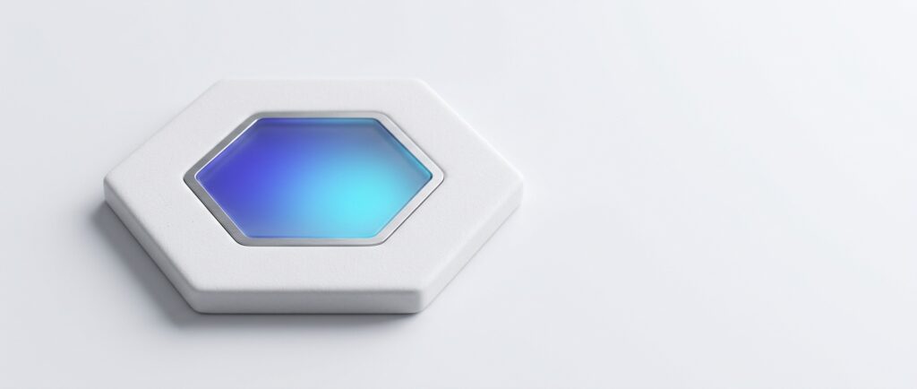 White ceramic hexagon tile with a smaller frosted glass hexagon set into its centre, lit from inside in indigo and cyan, on a light grey backdrop